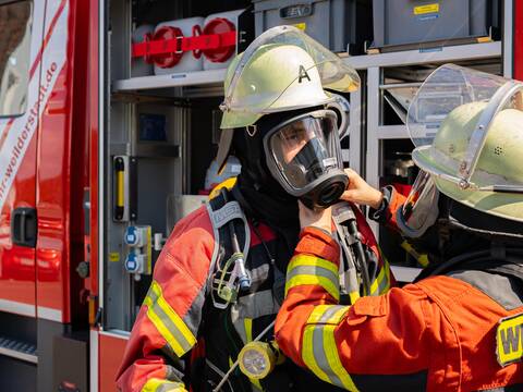 Feuerwehrleute beim Anlegen der Atemschutzmaske.