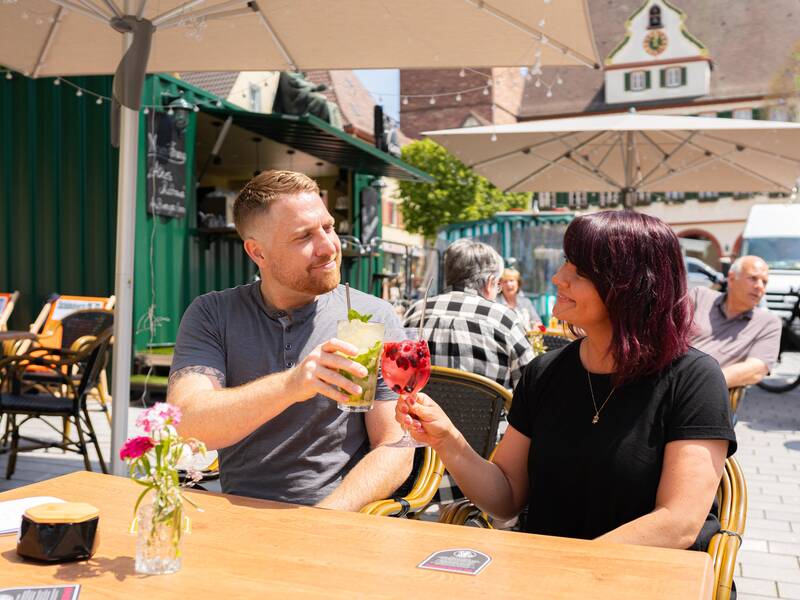 Zwei Personen genießen das gastronomische Angebot auf dem Marktplatz der Stadt.