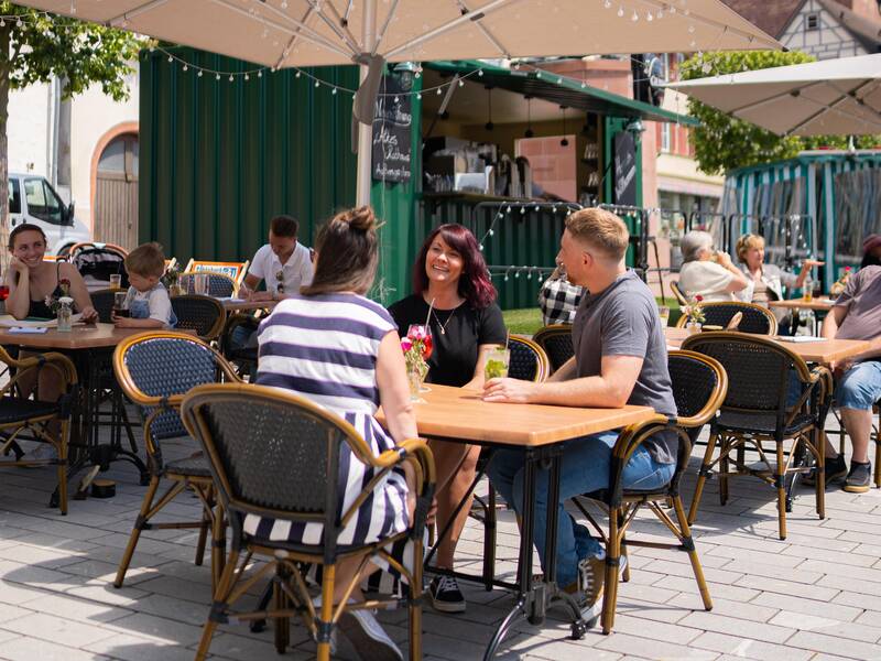 Eine Familie genießt das gastronomische Angebot auf dem Marktplatz der Stadt.