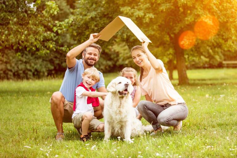 Familie mit Dach über dem Kopf im Garten als Symbol für den Hausbau.