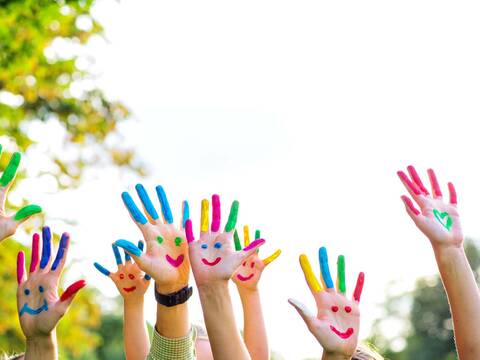 Eine Familie drückt ihre Freude über die bevorstehenden Ferien mit bunt bemalten Händen aus.