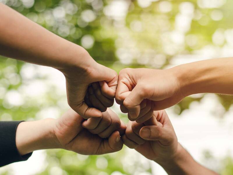 Vier engagierte Personen strecken ihre Fäuste in die Mitte.